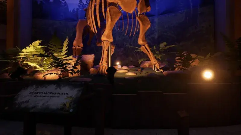 The feet of the reception Brontosaurus skeleton beside plants and a fossil display sign.